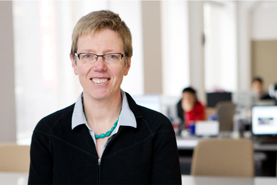 Jutta Treviranus from the Inclusive Design Research Centre. Jutta wears a black zip up sweater, blue dress shirt, and smart black framed spectacles.