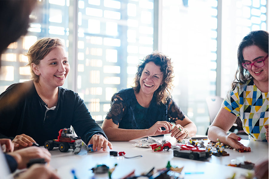 Gab, Rebecca, and Francesca sit around a table during a design workshop