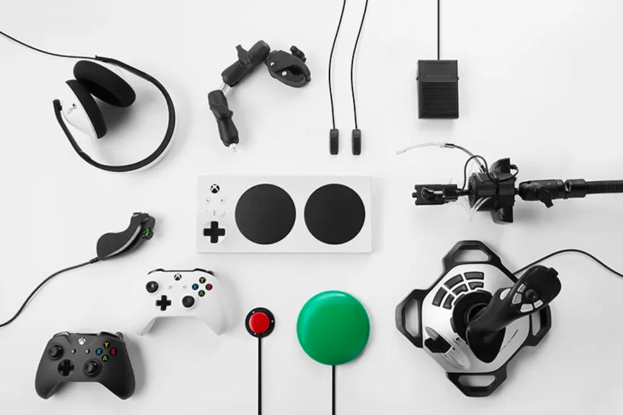 Seen from above, the Xbox adaptive controller surrounded by peripherals, set against a white background.