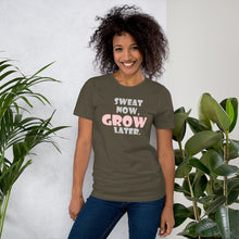Load image into Gallery viewer, A young brown smiling woman is standing wearing a Sweat Now, Grow Later army colored Short-Sleeve Women T-Shirt paired with blue denim. She is facing to the front and leaing
