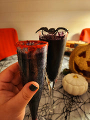 Halloween party drinks using black edible glitter, sparkling wine and red edible glitter around the edge