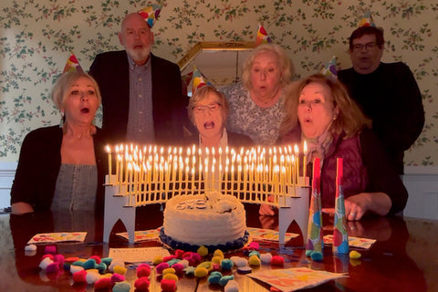 Family sings Happy Birthday with a Celebration Stadium candle holder lit with 90th birthday candles in the foreground.