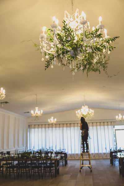 A florist installs hanging greenery at a venue
