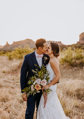 Bride and groom holding flowers in Sedona at magic hour