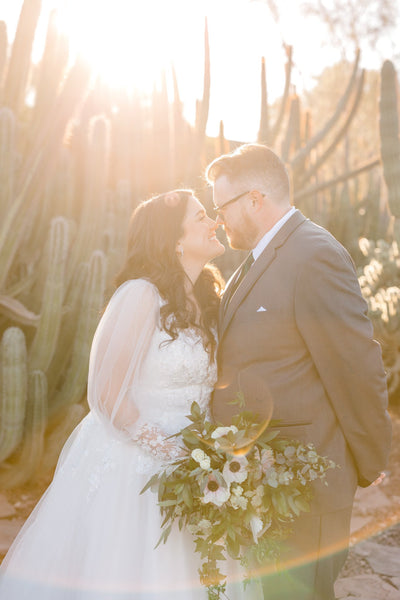 A bride and groom pose during magic hour with a bouquet