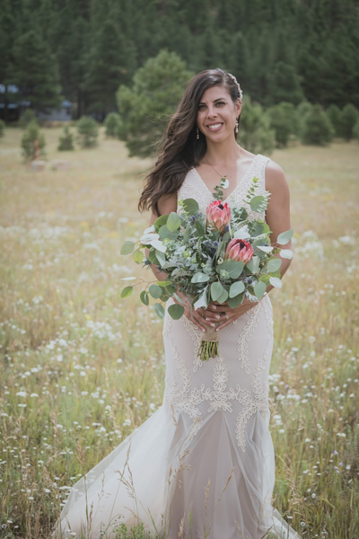 A bride holds her eucalyptus bouquet in a flagstaff az meadow