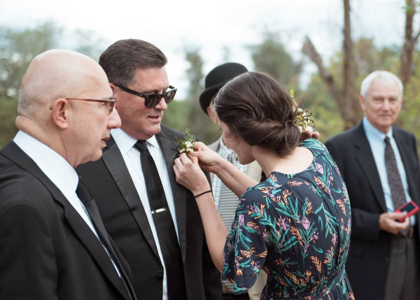 Florist pins a boutonniere on the father of the bride at a Prescott Wedding