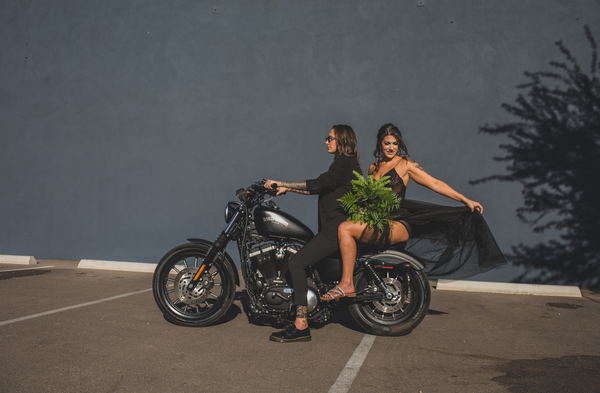 Two brides on a motorcycle with a green bouquet