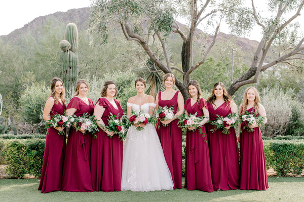 A Bridal Party in burgundy dresses pose with their flowers at El Chorro in Paradise Valley