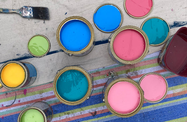 flat lay image of pink, blue, green and yellow british paint paint tins