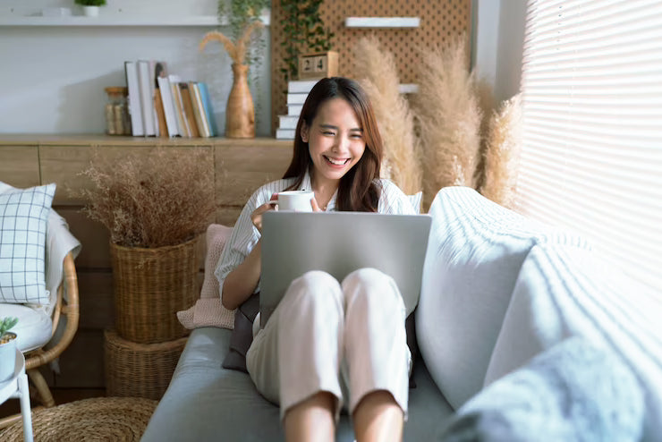Happy teacher at home holding a cup of coffee browsing her laptop