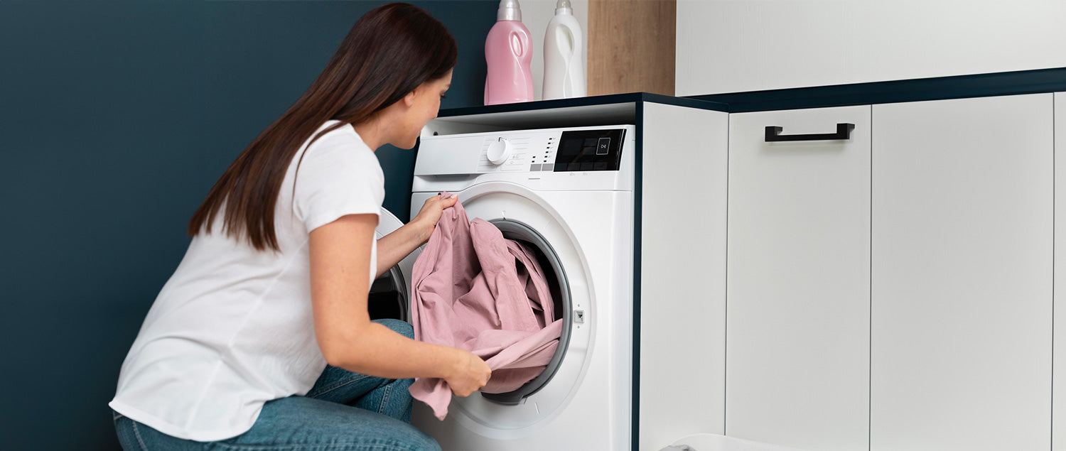woman putting in clothes into her washing machine