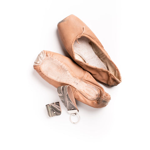 Sustainable textiles project with The Royal Opera House.  Seen here are ballet slippers, worn for one performance, the leather base worn.  The slipper is deconstructed and leather marbled to create marbled leather key fob, on a silver key ring and a cable tidy with a silver button closure