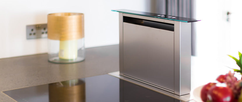 A stainless steel downdraft rangehood rising from a kitchen island.