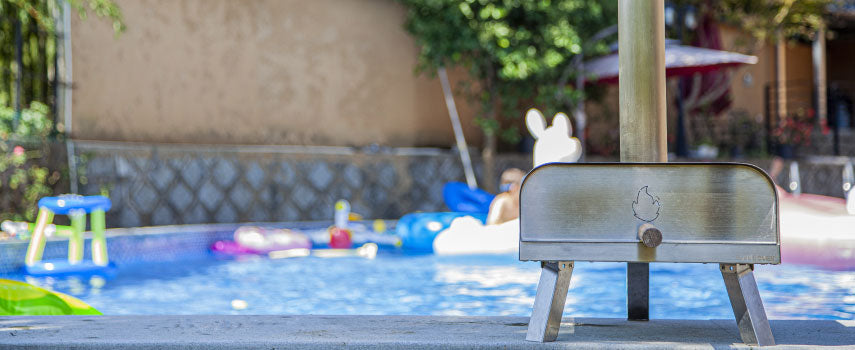 Four à pizza flameoven posé sur le sol à coté d'une piscine en extérieur