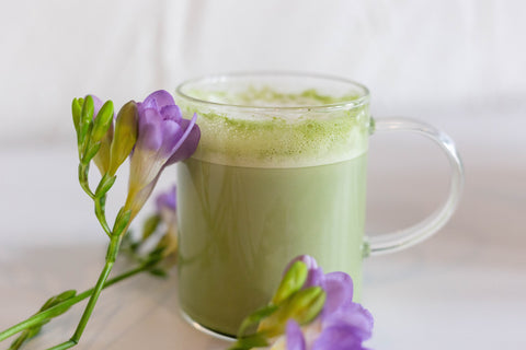 matcha latte in clear mug with purple flowers