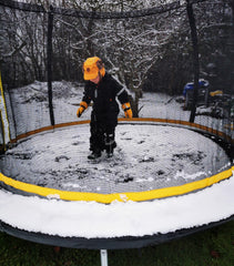 Boy jumping on an outdoor trampoline in snow