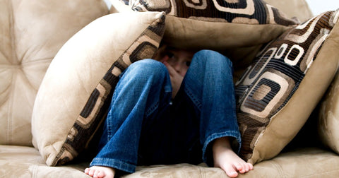 child hiding in pillows