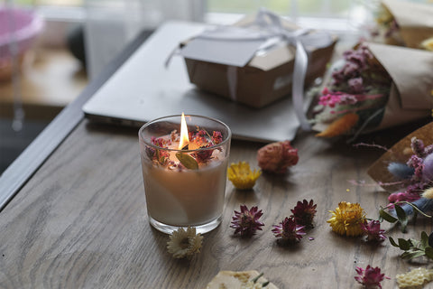 lit candle surrounded by herbs on a reading table in soft lit room