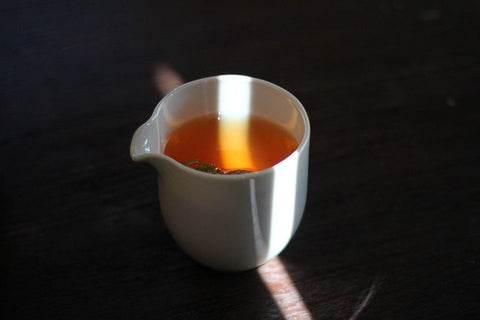 A fairness cup filled with an amber brew of black tea.