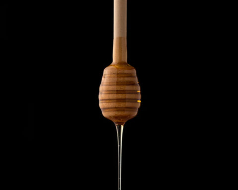 A honey dipper dripping with honey