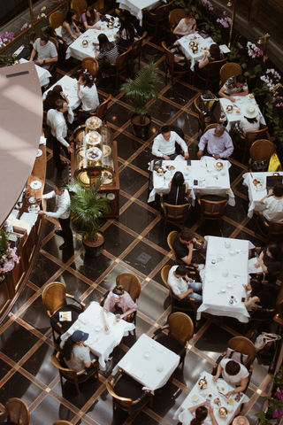 An overhead view of patrons in a fine restaurant being served tea