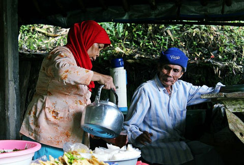 An elderly woman serving her husband tea outdoors