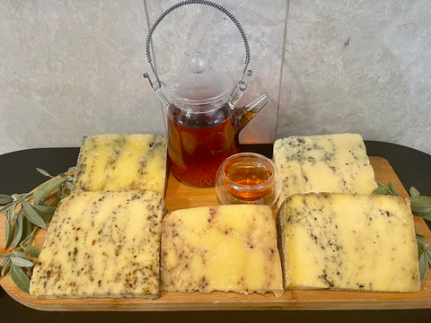 5 different cheeses with a glass teapot and teacup in the center.