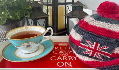 A teal and white cup and saucer commemorating Queen Elizabeth II and a winter cap with the British flag