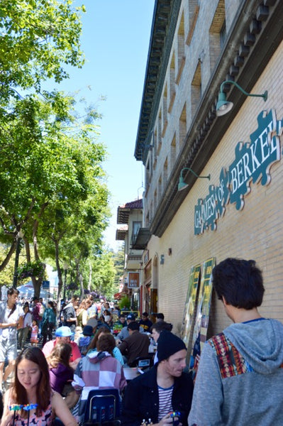 Outdoor view of the Games of Berkeley store with players testing out local games on tables.