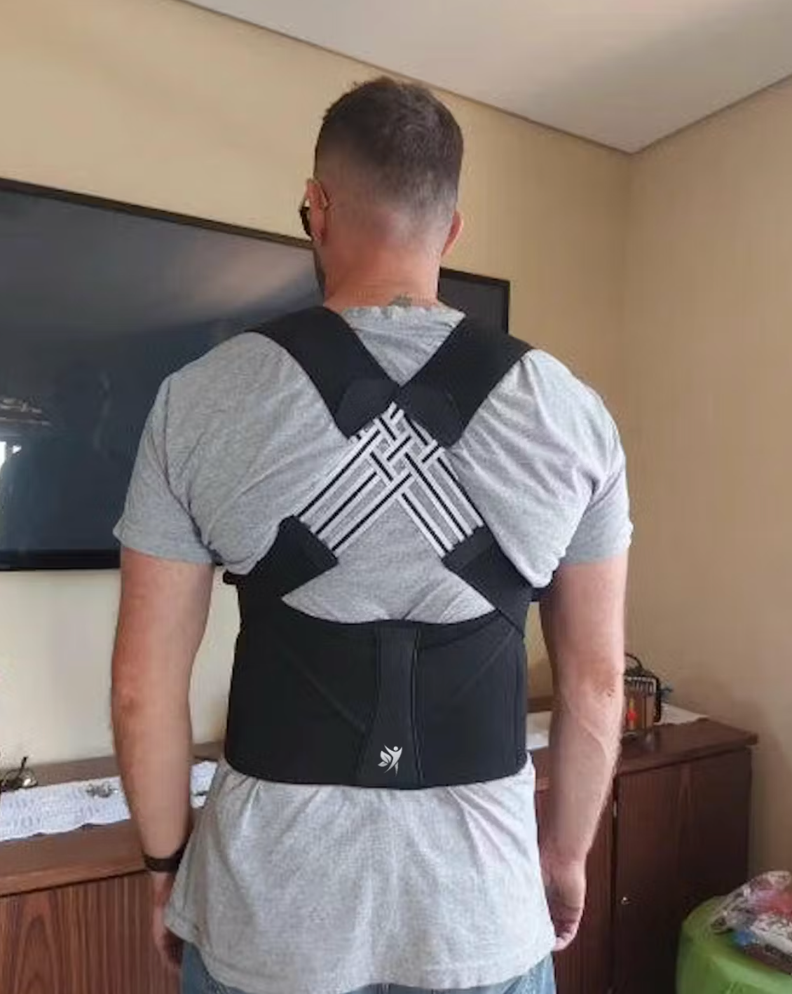 Man wearing a posture-correcting back brace in a room.