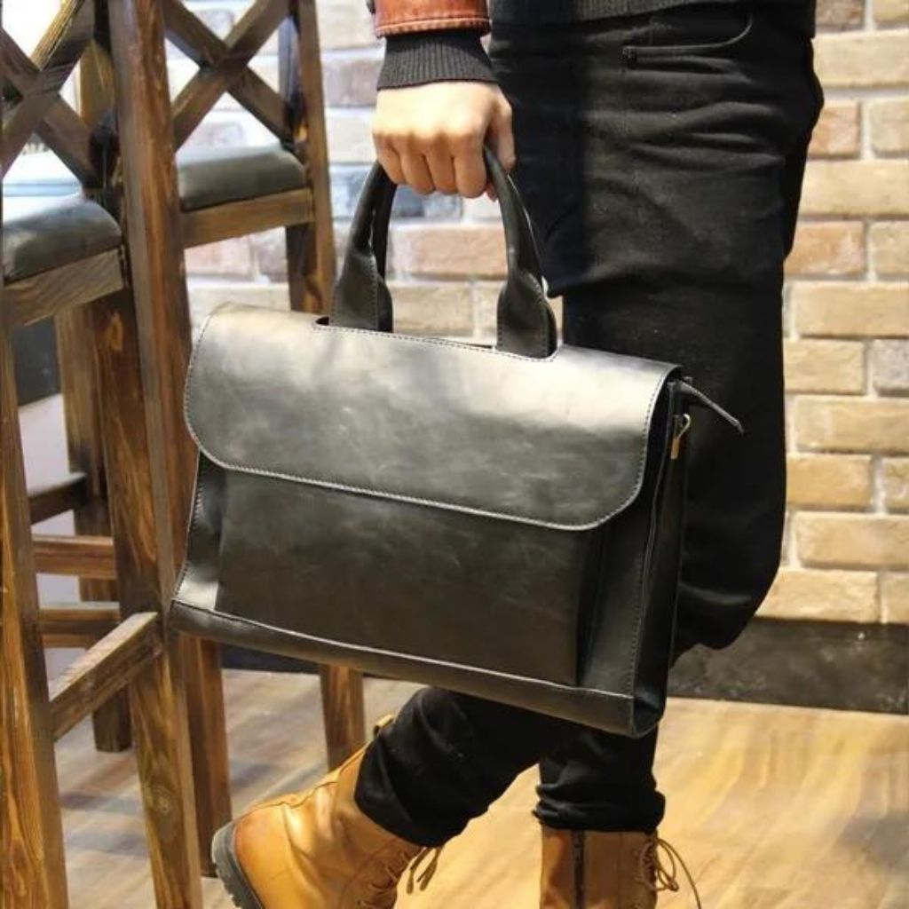 Man holding a black leather messenger bag from the luxury fashion brand Gentcreate