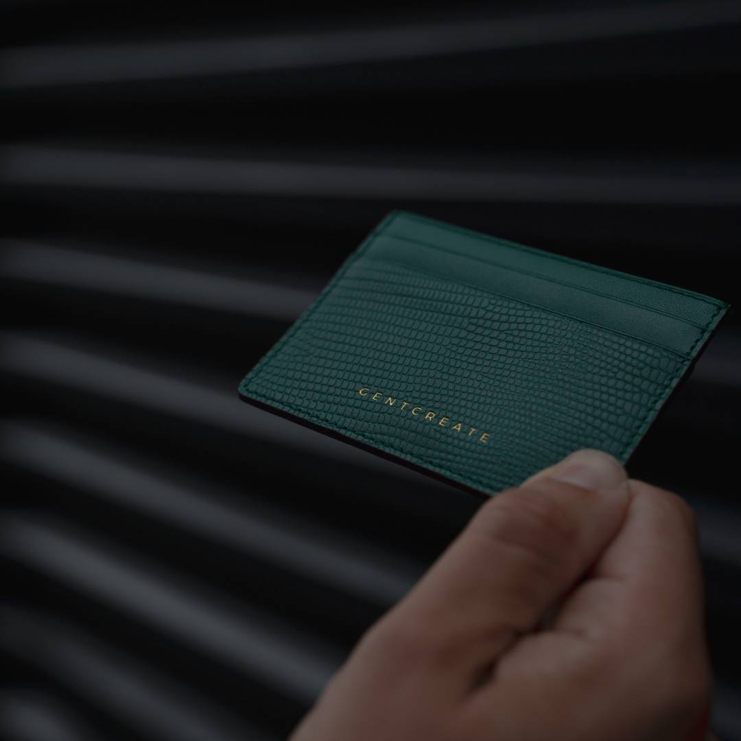 The man holds a green leather cardholder by Gentcreate, a luxury tech brand.