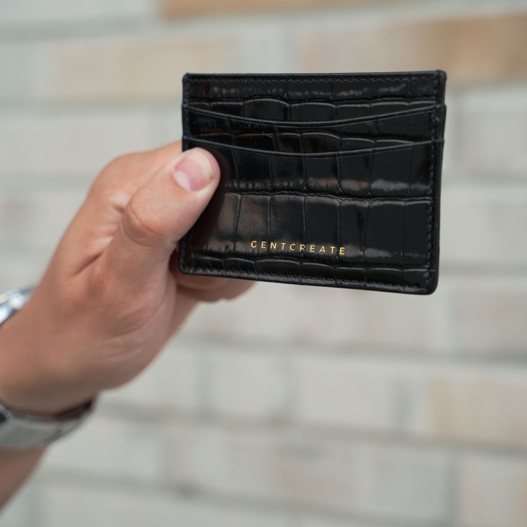 The man holds a black glossy leather cardholder from the luxury tech brand Gentcreate.