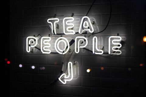 neon sign saying tea people and arrow pointing to the left