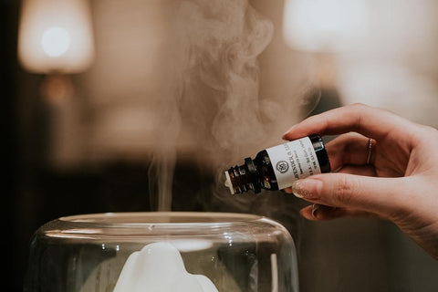 hand pouring essential oil into a steam diffuser