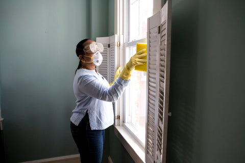 woman cleaning windows wearing a mask