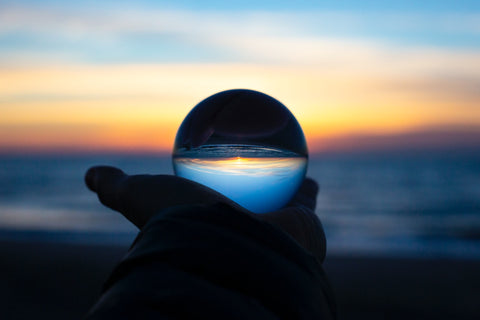 person holding a glass globe with earth and sky inside it