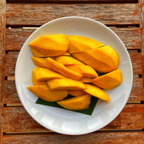 mango cut up on a plate on a wooden slatted table