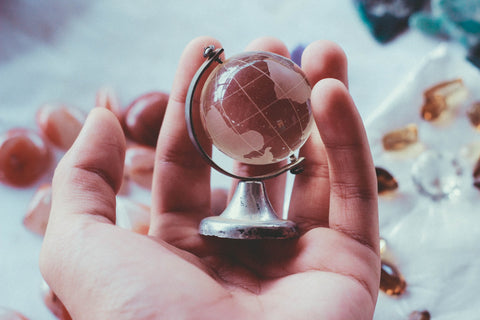 persons hand holding little miniature world globe