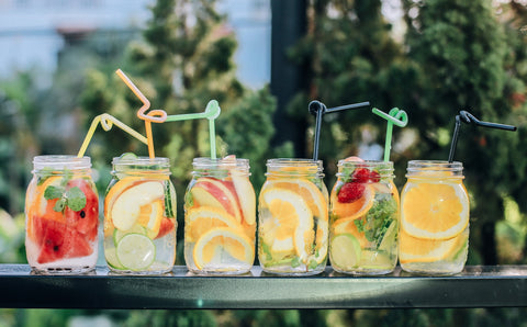 six glass containers with infused water and fruit drinks