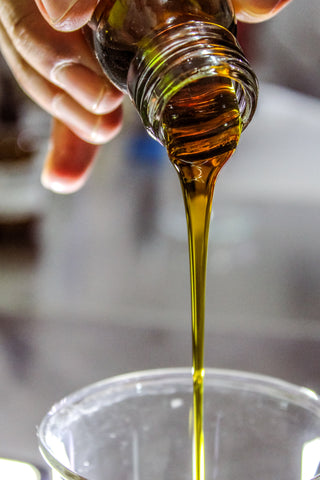 natural essential oil being poured into a glass container