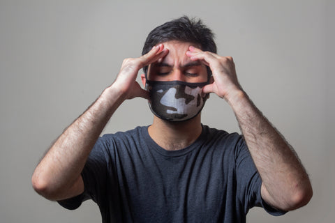 man wearing mask holding his head