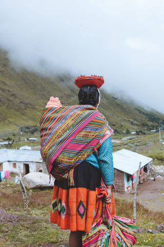 Mother carries her child on her back while looking over the town.