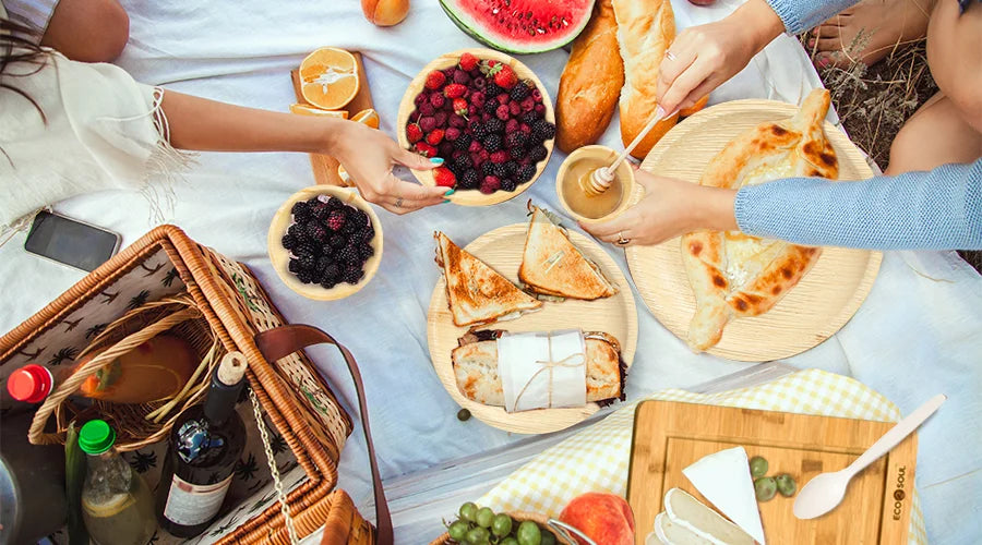 An outdoor dining setup with a variety of food and drinks on eco-friendly serving items.