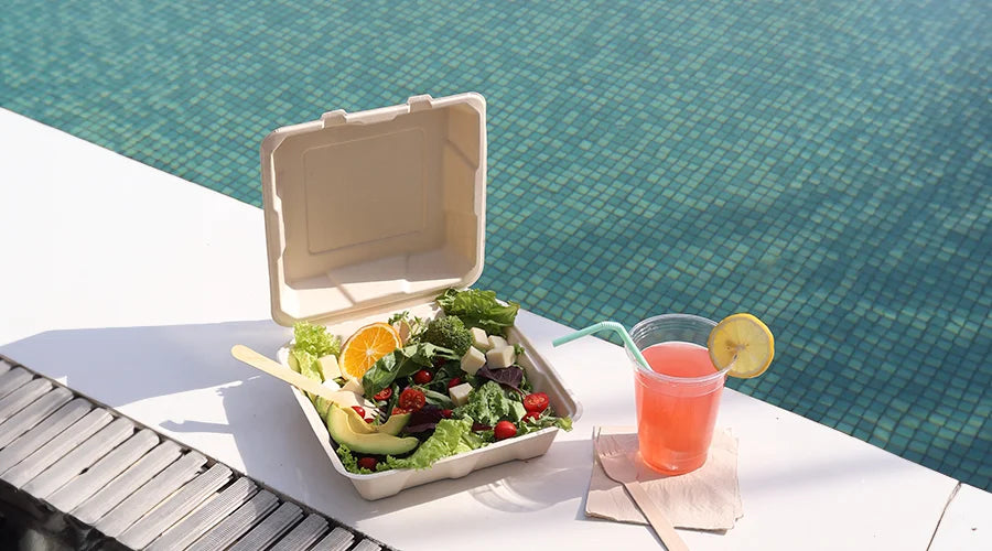 Vegetables served on Bagasse clamshell and a glass of juice with compostable straws