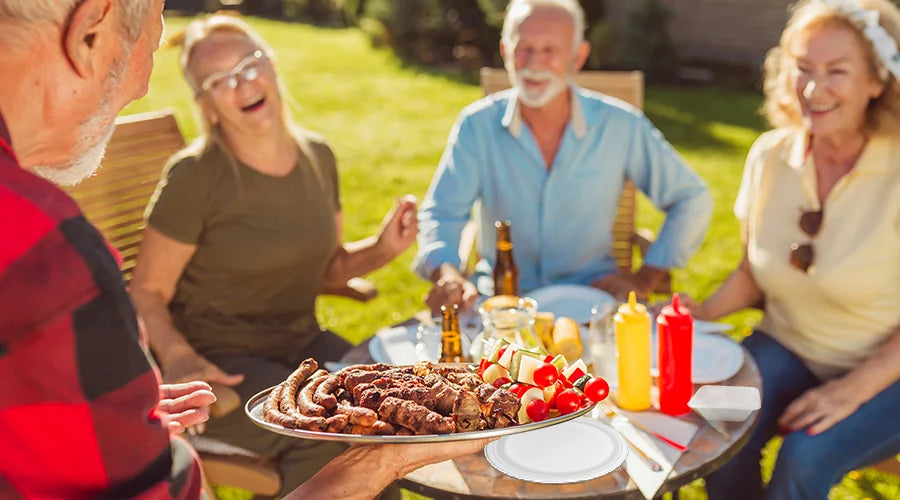 Senior couple having a barbecue with eco-friendly picnic supplies.