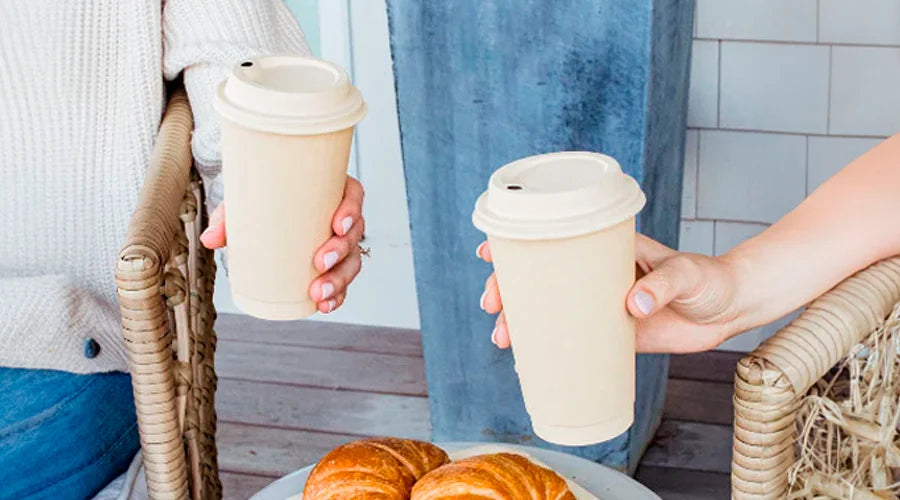 Two individuals holding compostable hot cups filled with coffee.