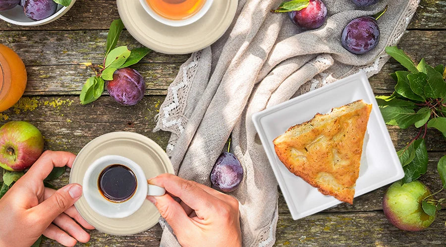 Person holding a cup of coffee and a slice of pie on compostable plates and cups at an eco-friendly tea party.