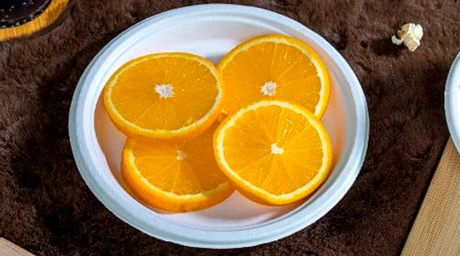 Orange slices on a plate with a cup of coffee, served on Sugarcane Bagasse Plates.